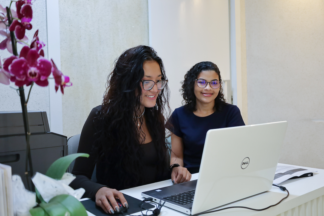 Equipe da recepção da clínica JR Implantes atendendo com sorriso